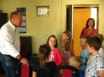 Grupa dzieci stoi w gabinecie Naczelnika Urzędu. Po lewej Pan Naczelnik rozmawia z dziećmi.
