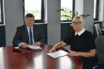 Dyrektor Izby Administracji Skarbowej w Poznaniu i Wielkopolski Wojewódzkim Lekarzem Weterynarii siedzą przy stole i podpisują porozumienie.