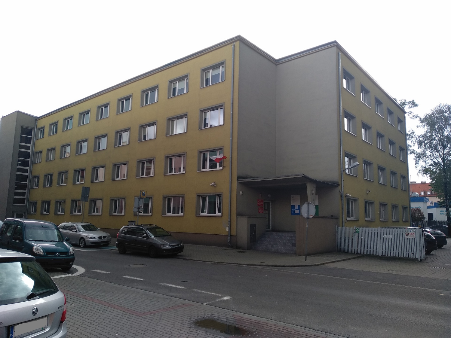 Na zdjęciu 3 - piętrowy budynek, elewacja miodowo - szara.