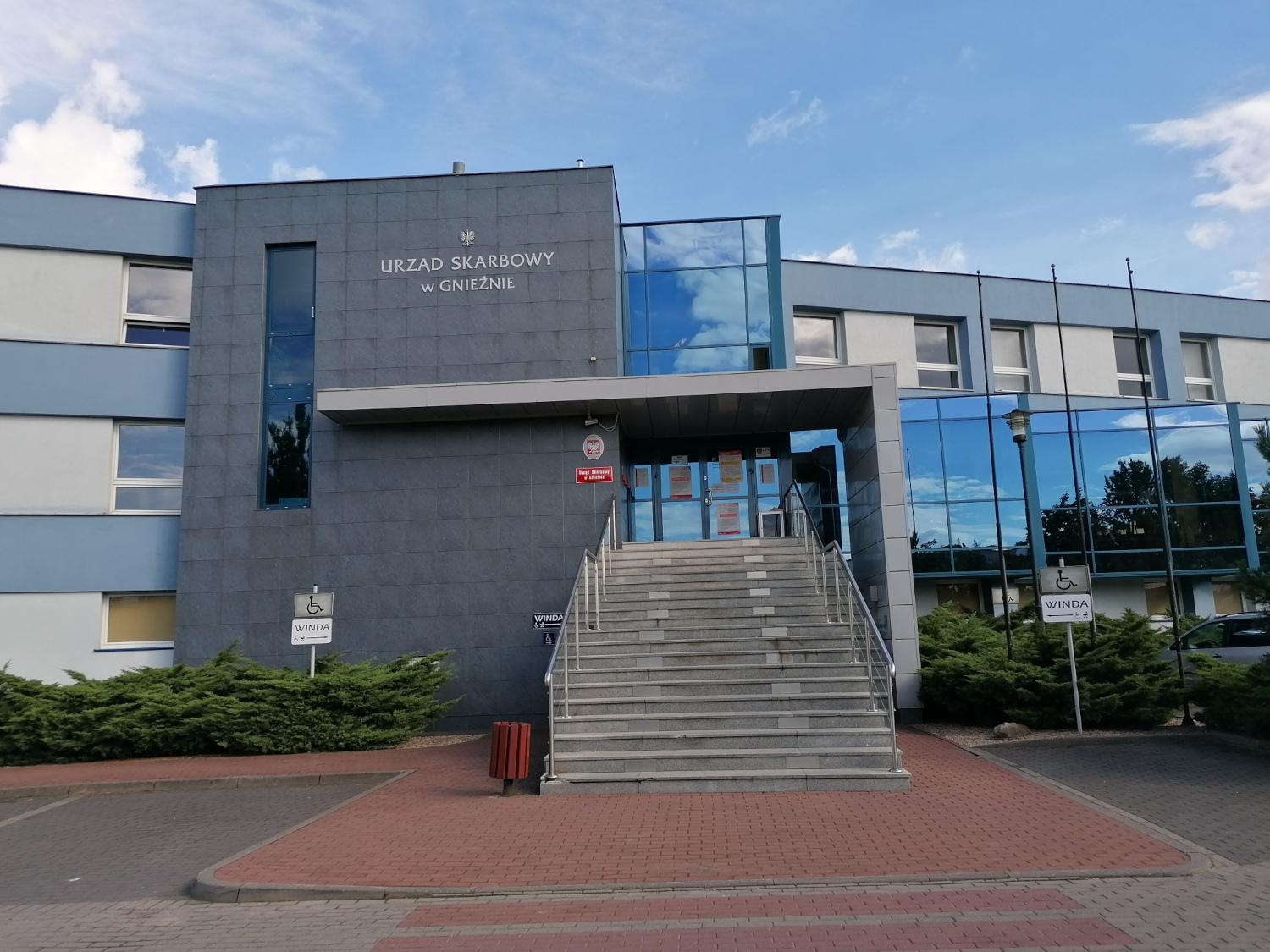 Na zdjęciu budynek w niebiesko - szarej elewacji częściowo przeszklony