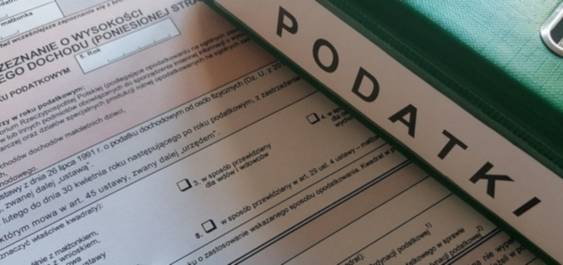 Na zdjęciu formularz podatkowy i segregator w zielonym kolorze