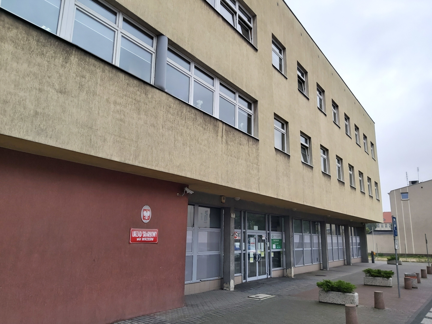 Na zdjęciu budynek w jasno - ceglastej elewacji