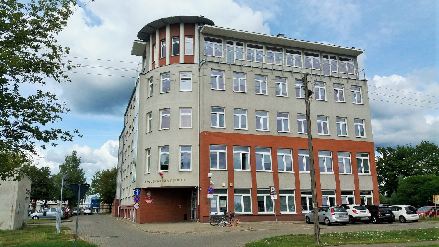 Na zdjęciu budynek w szarej elewacji z elementami w kolorze ceglastym
