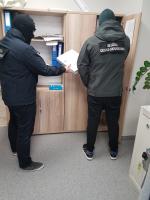 Dwóch funkcjonariuszy stojących tyłem przy szafie z dokumentacją