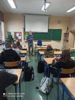 sala szkolna, w ławkach siedzą uczniowie, między ławkami chodzi wykładowca