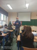 sala szkolna, w ławkach siedzą uczniowie, między ławkami chodzi wykładowca