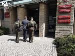dwaj umundurowani funkcjonariusze KAS wprowadzają mężczyznę do budynku Prokuratury Rejonowej w Poznaniu