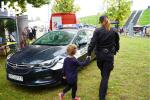 Funkcjonariusz Służby Celno-Skarbowej pokazuje dziecku samochód służbowy