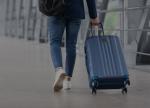 Mężczyzna ciągnący walizkę po płycie lotniska