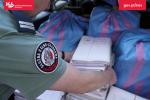 ręka funkcjonariusza Służby Celno-Skarbowej odkładająca akta do bagażnika samochodu
