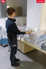 Funkcjonariuszka Służby Celno-Skarbowej liczy paczki papierów leżące na stole