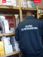 Funkcjonariusz w trakcie kontroli stojący tyłem przy półkach magazynowych