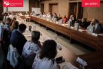 Grupa uczestników spotkania siedzi przy stołach i dyskutuje
