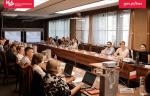 Grupa uczestników spotkania siedzi przy stołach i dyskutuje
