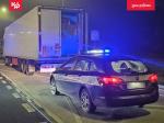 Na poboczu stoi samochód ciężary. Przed nim stoi radiowóz Służby Celno-Skarbowej.