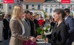 Kobieta w czarnej marynarce podaję rękę kobiecie w beżowej marynarce obok pracownicy wielkopolskiej KAS ustawieni w równym rzędzie