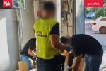 Pomieszczenie gospodarcze. Funkcjonariusze Służby Celno-Skarbowej sprawdzają szare kartony.