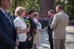 Dyrektor Izby Skarbowej w Poznaniu gratuluje i wręcza róże stojącym w rzędzie odznaczonym.