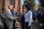 Dyrektor Izby Skarbowej w Poznaniu gratuluje i wręcza róże stojącym w rzędzie odznaczonym.