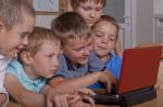 grupa dzieci spogląda z zaciekawieniem do laptopa