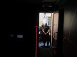 Dwóch funkcjonariuszy w kominiarkach stojących w drzwiach kontrolowanego lokalu - w tle samochód służbowy