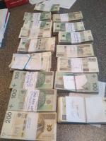 Na stole rozłożone są posortowane pliki banknotów.